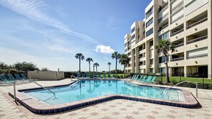 A swimming pool with lounge chairs and a multi-story building in the background. - Beautiful First Floor Oceanfront Condo at Amelia Surf and Racquet-Close to Pool! (Fernandina Beach)