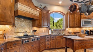 A kitchen with wooden cabinets, a stove, and a large window. - Rockin' B Ranch Summit House (Pipe Creek)