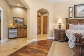 A bedroom with a large bed, wooden headboard, a nightstand, and a bedside table with a lamp.