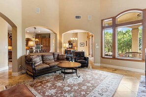 A spacious living room with a large sofa, a coffee table, and a dining area with chairs.