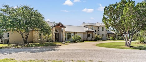 A two-story house with a stone facade, a covered porch, and a driveway leading to the entrance.