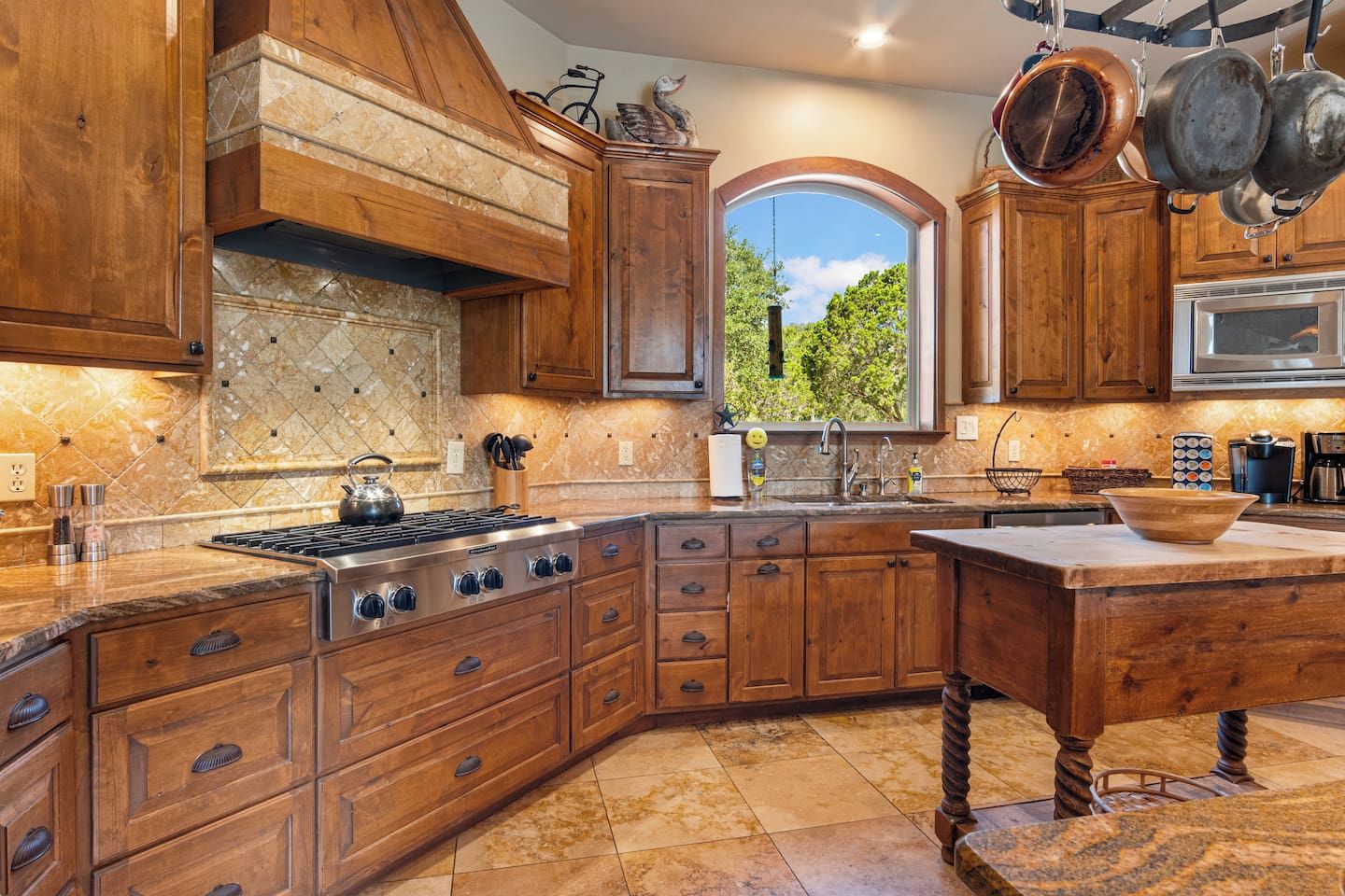 A kitchen with wooden cabinets, a stove, and a window with a view of greenery.