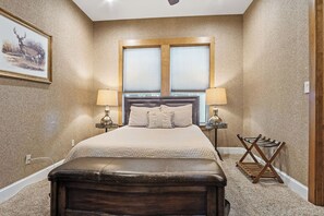 A bedroom with a large bed, two bedside lamps, a headboard, and a framed picture on the wall. - Rockin B Summit | Luxury Retreat with Pool & Creek (Pipe Creek)