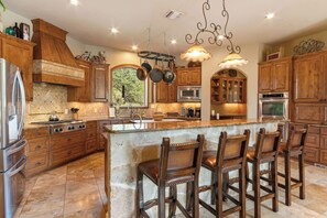 A spacious kitchen with wooden cabinets, a large island with bar stools, and modern appliances.