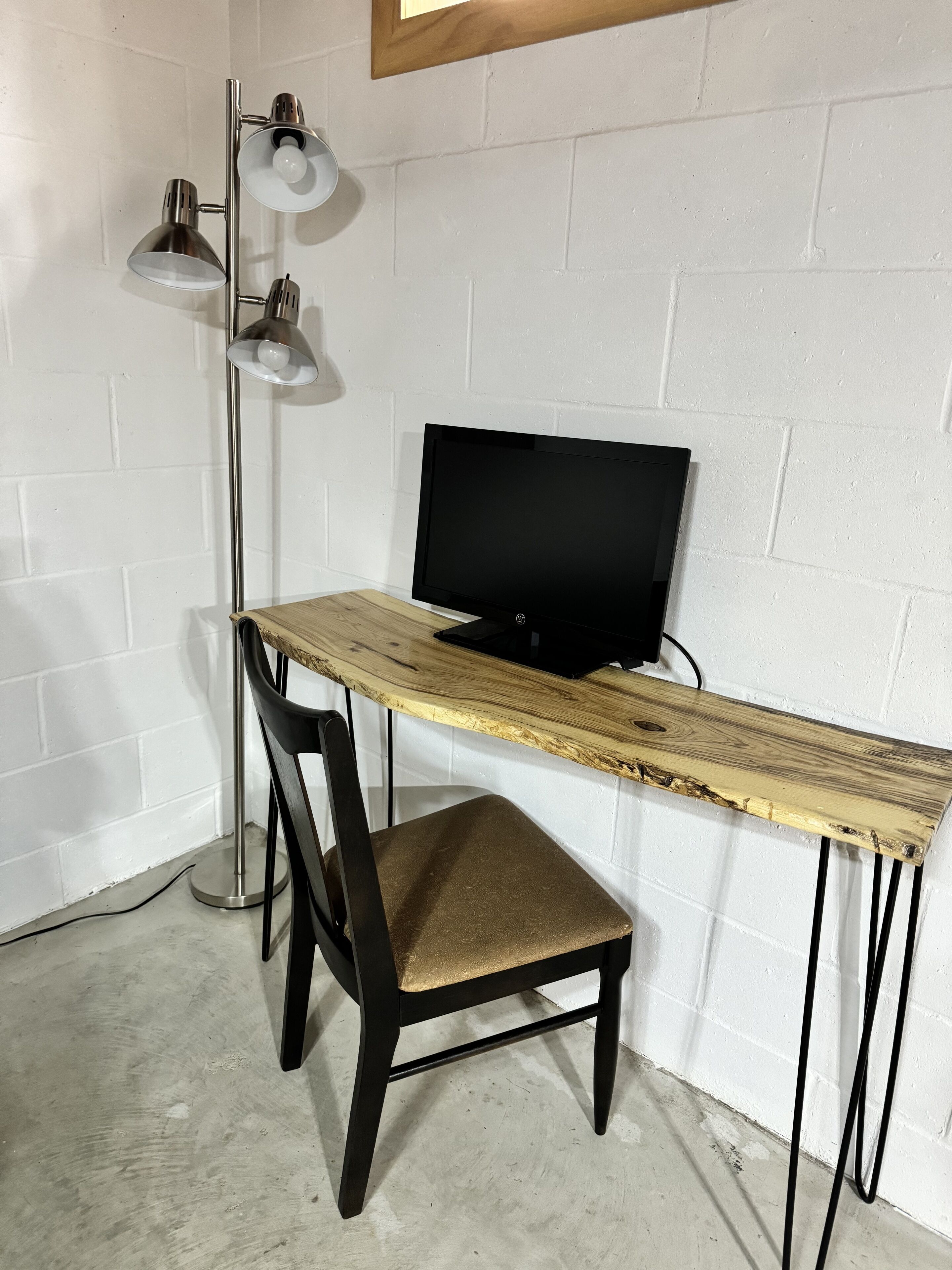 A workspace with a wooden desk, a black chair, and a floor lamp.