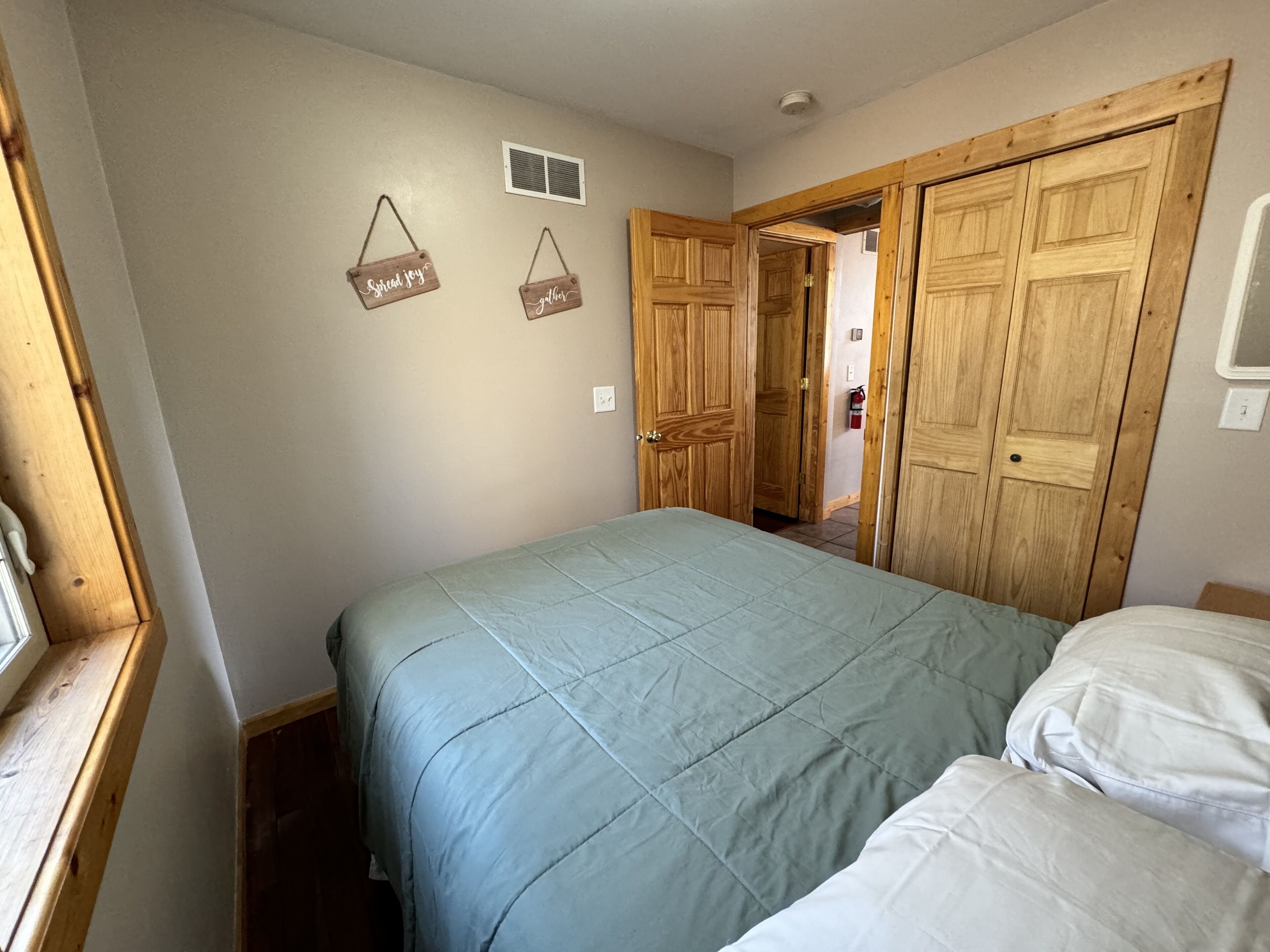 A bedroom with a bed, wooden wardrobe, and two wall-mounted signs.