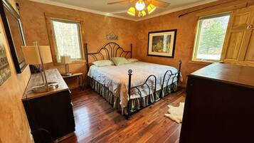 A bedroom with a bed, a ceiling fan, a desk, and a window.
