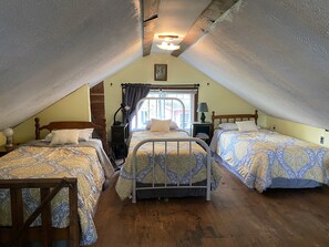 Une chambre mansardée chaleureuse, dotée de deux lits, de têtes de lit en bois et d’un plafond en pente.