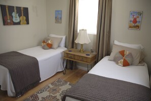 A hotel room with two single beds, a nightstand, a lamp, and a window with curtains. - Home Away From Home/Pets Welcome (Wilton Manors)