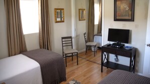 Habitación de hotel con dos camas, un escritorio con televisor y una silla.