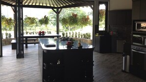 A modern kitchen with a central island, a built-in oven, and a dining area with a table and chairs. - Beautiful Lake House outside of Medellin Colombia (55 Kilometers) (Amaga)