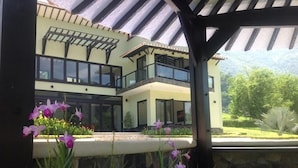 A modern two-story house with large windows and a covered patio area. - Beautiful Lake House outside of Medellin Colombia (55 Kilometers) (Amaga)