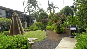 A landscaped garden with a gravel path, a covered picnic table, and a barbecue grill. - PERFECT KAUAI Condo!! Steps from Beach/2bd2bth Washer/Dryer AC -Free Parking (Kapaa)