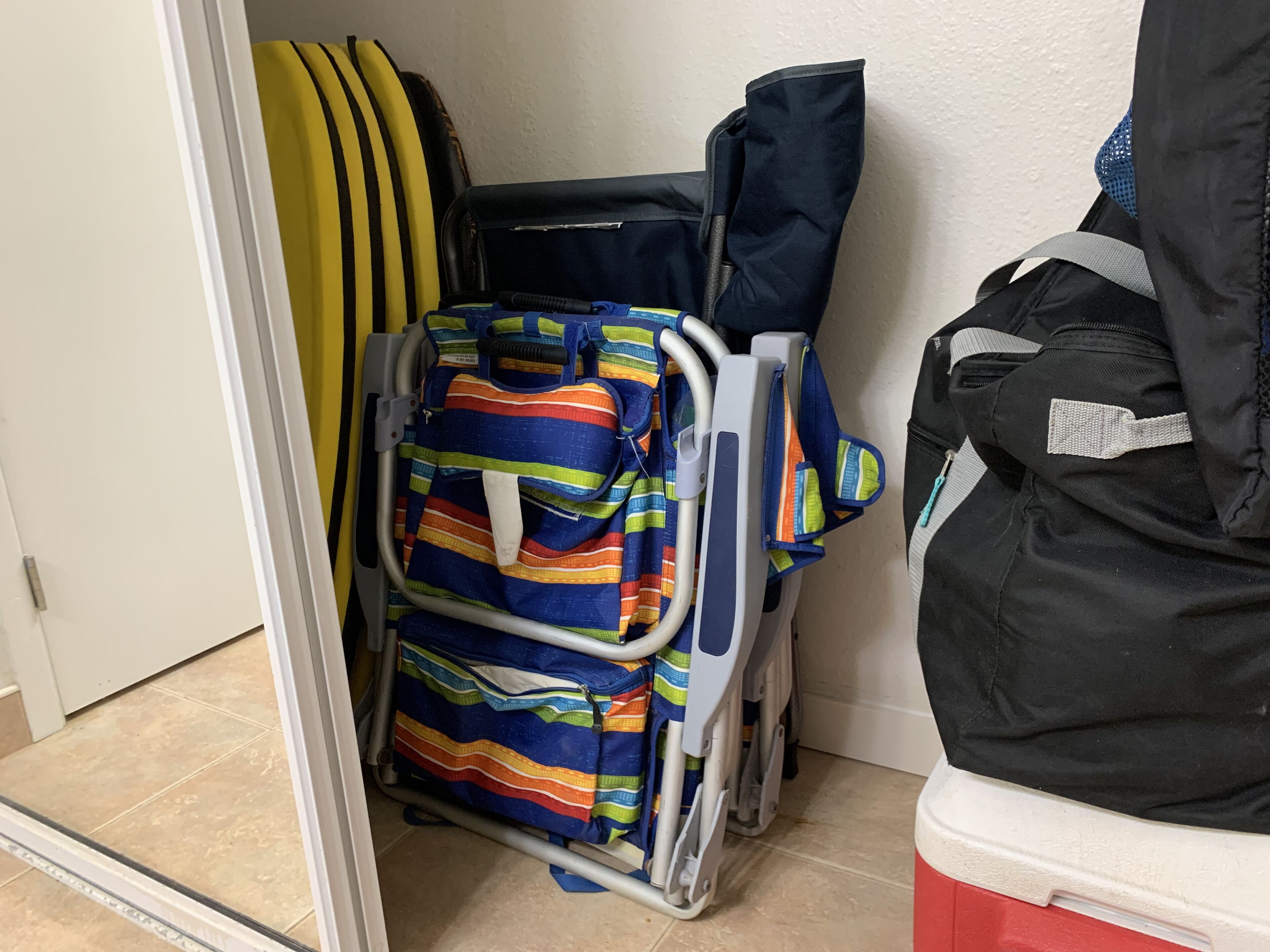 A room with a wheelchair, a colorful striped bag, and a black jacket on a chair.