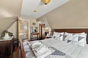 A bedroom with a large bed, a wooden nightstand, a dresser, a mirror, and a window.