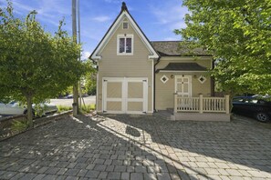 A two-story building with a garage, a front porch with a railing, and a paved driveway.
