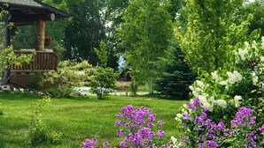 A wooden cabin with a sloped roof, surrounded by lush green grass and trees.
