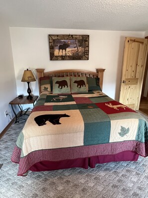A bedroom with a bed, a lamp, a painting, and a wooden door.