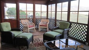A covered porch with wicker furniture, a glass table, and a view of a grassy area. - EMIGRANT LODGE - 4 bedroom home with central airconditioning (Emigrant)