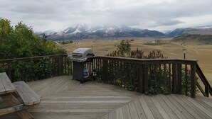 A wooden deck with a barbecue grill and a water bottle, overlooking a mountainous landscape with snow-capped peaks. - EMIGRANT LODGE - 4 bedroom home with central airconditioning (Emigrant)