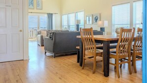A spacious living room with a dining area, wooden flooring, and large windows. - RARE 6 bedroom, 4 bath OCEANFRONT home, wonderful views & breathtaking sunsets! (Edisto Beach)