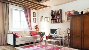 Een woonkamer met een bank, een salontafel, een televisie en een boekenkast.