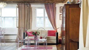Een kamer met een bed, een slaapbank, een houten kast en een raam met gordijnen.