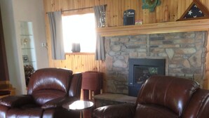 A living room with two brown leather recliners, a stone fireplace, and a small round table.