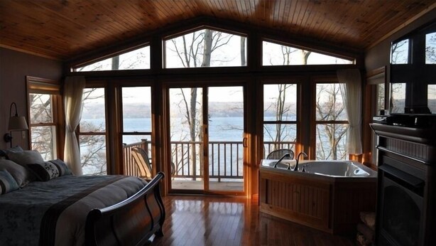 A cozy cabin with a large bed, a hot tub, and a fireplace.