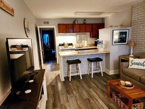 Cozy living space with a kitchen area, wooden coffee table, and a framed picture on the wall.