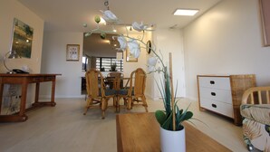 A dining area with a wooden table and chairs, a potted plant, and a white cabinet. - Upgraded 1BR Condo Ocean View - Kitchen, FREE parking, WiFi (Honolulu)