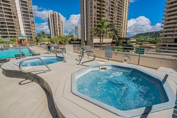 A rooftop pool area with hot tubs, lounge chairs, and a sign for 'Holler Spa.'