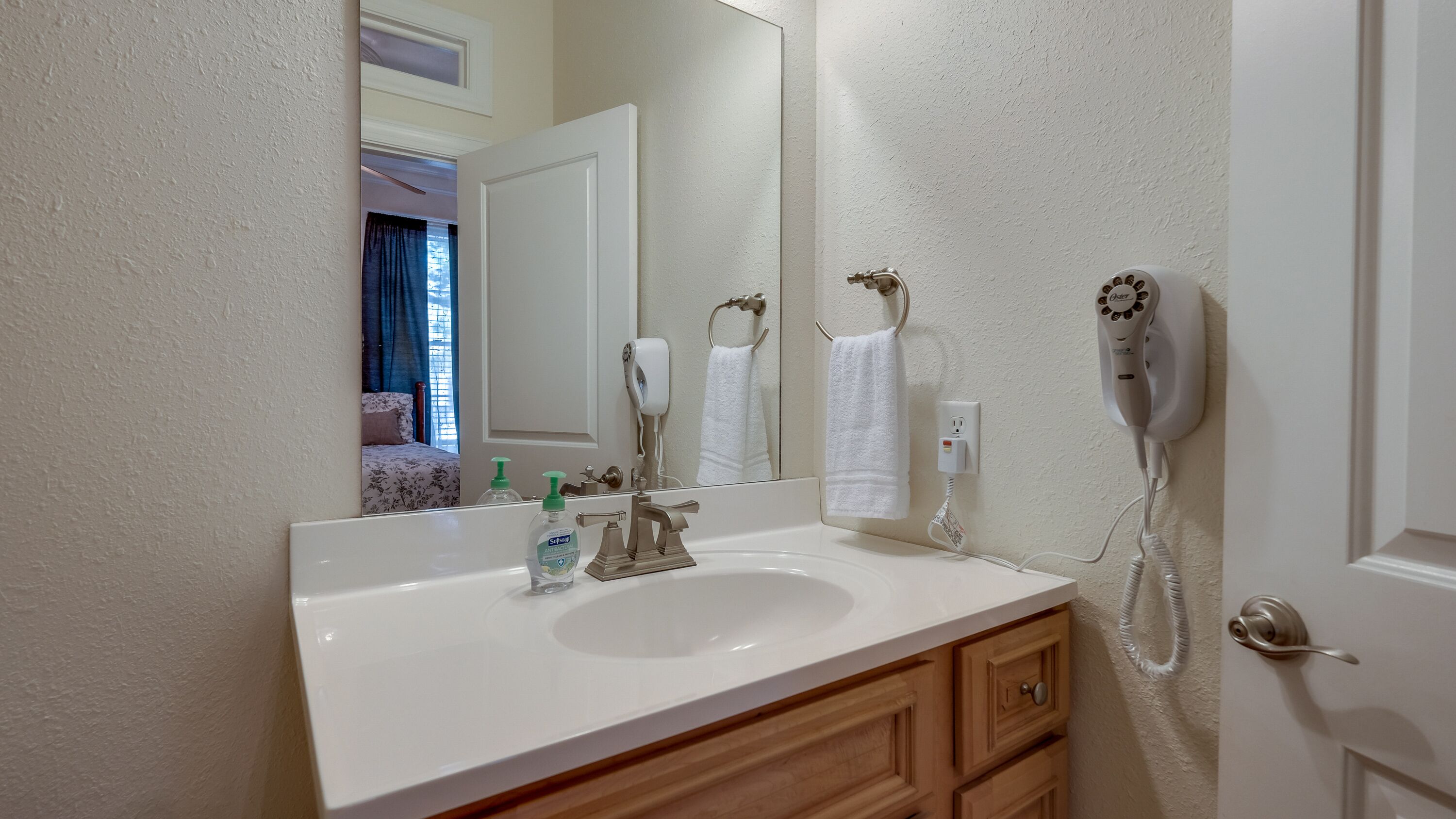 A bathroom with a white sink, a mirror, a hairdryer, and a towel rack.