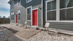 Ein Haus mit roter Tür, einer überdachten Terrasse mit Stühlen und einem Schotterweg.