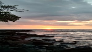 Une côte rocheuse avec un coucher de soleil sur l’océan.