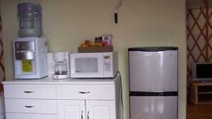 Une petite cuisine équipée d’un distributeur d’eau, d’une machine à café, d’un four à micro-ondes et d’un réfrigérateur.