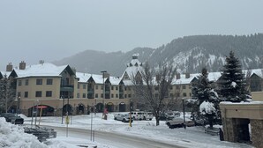 Un hôtel composé de plusieurs bâtiments, un parking rempli de voitures et, en arrière-plan, une montagne enneigée.
