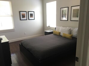 Une chambre à coucher avec un lit, deux tables de chevet et des tableaux encadrés accrochés au mur.