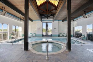 An indoor swimming pool with a sunroof, lounge chairs, and a view of palm trees. - Shoalwater 906 Gulf-Front Corner Condo with Beach Views! 3 bedrooms (Orange Beach)