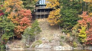 A cabin with a balcony overlooking a lake, surrounded by autumn-colored trees. - Serenity on Cedar-Lakefront Cabin- 10 boats-Swim/Fish/Boat, Starlink & Hulu Live (Tuckasegee)