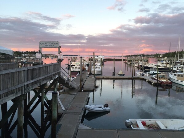 A marina with boats docked, a wooden pier, and a sign welcoming patrons and guests.