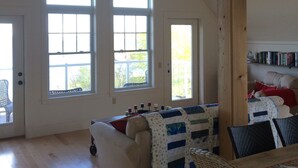 Un salón espacioso con techo alto, vigas de madera y ventanas grandes.