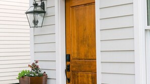 Una casa blanca con puerta principal de madera, buzón y planta en maceta.