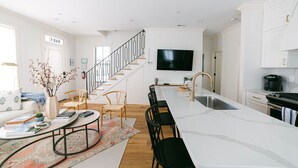 Una cocina moderna con una isla grande, armarios blancos e integrada una televisión.