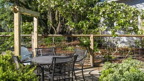 Eine Terrasses mit Holz-Pergola, Metallstühlen und einem Tisch.