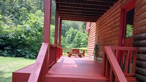 Una terraza de madera con barandillas rojas que conduce a una cabaña con puerta roja.