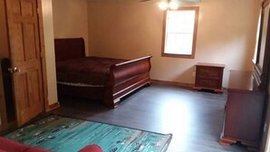 Un dormitorio con cama, cómoda, mesita de noche y ventana.