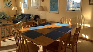 A dining area with a wooden table and chairs, a blue placemat, and a map of the Outer Banks on the wall. - Frisco Beach House! Some ocean views! Easy walk to the beach!  (Frisco)