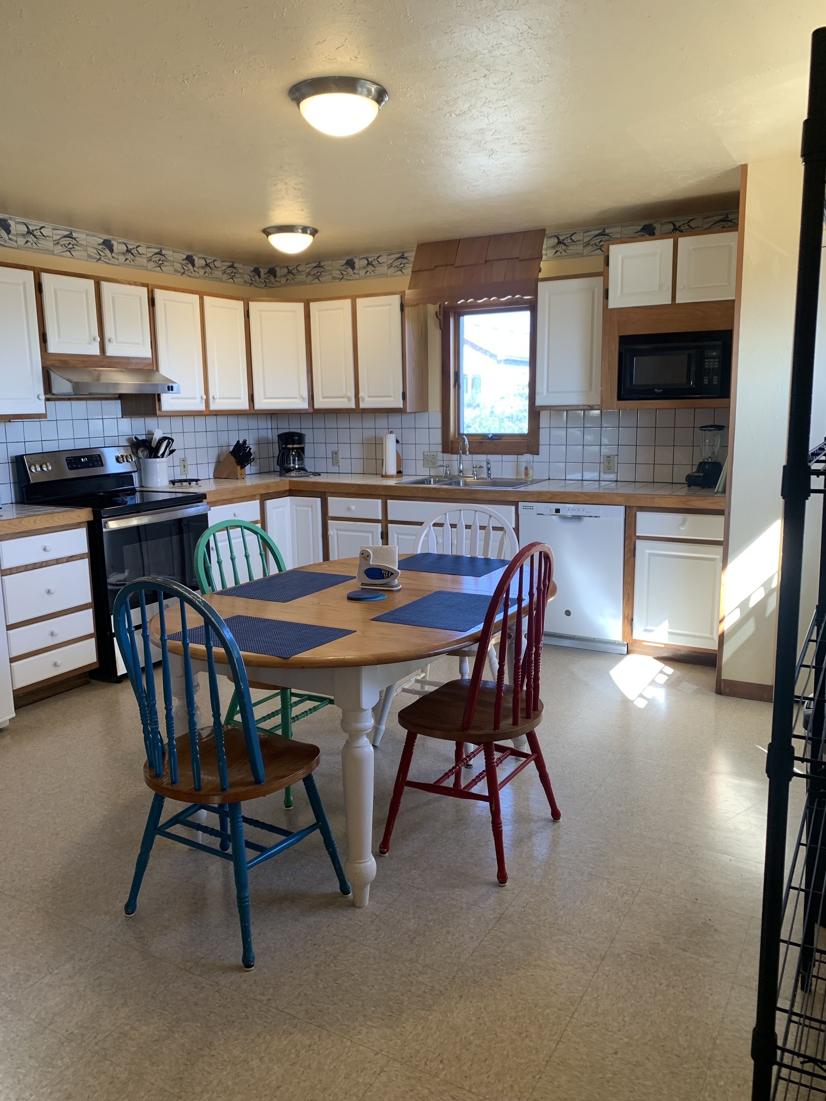 A kitchen with white cabinets, a wooden countertop, a dining table with four chairs, and a microwave above the counter.