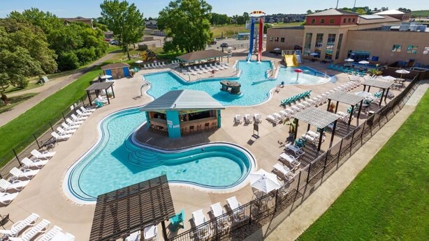 Amplia zona de piscina al aire libre con varias piscinas, sillas de descanso y una zona de bar.